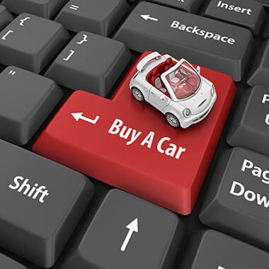 Keyboard with the enter button in red instead reading 'Buy A Car' and a small white toy car sitting on it