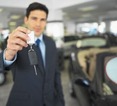 Car dealer holding up a car key in a car dealership