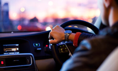 Hands of a young driver on a steering wheel driving at night