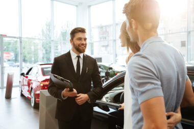A car dealer talking to two people in a showroom