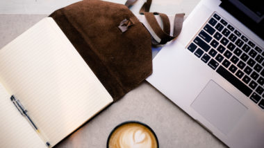 Notepad, laptop and cappuccino on a table