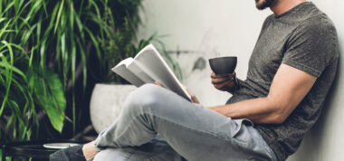 Person sitting relaxing reading a book and drinking a coffee