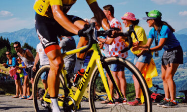 Low photo of Tour de France cyclist on yellow bike with people cheering in the background