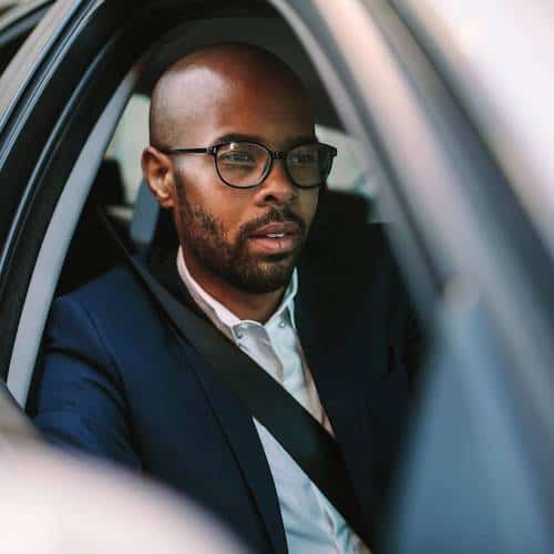 Man wearing glasses sitting behind the wheel of the car with the window down