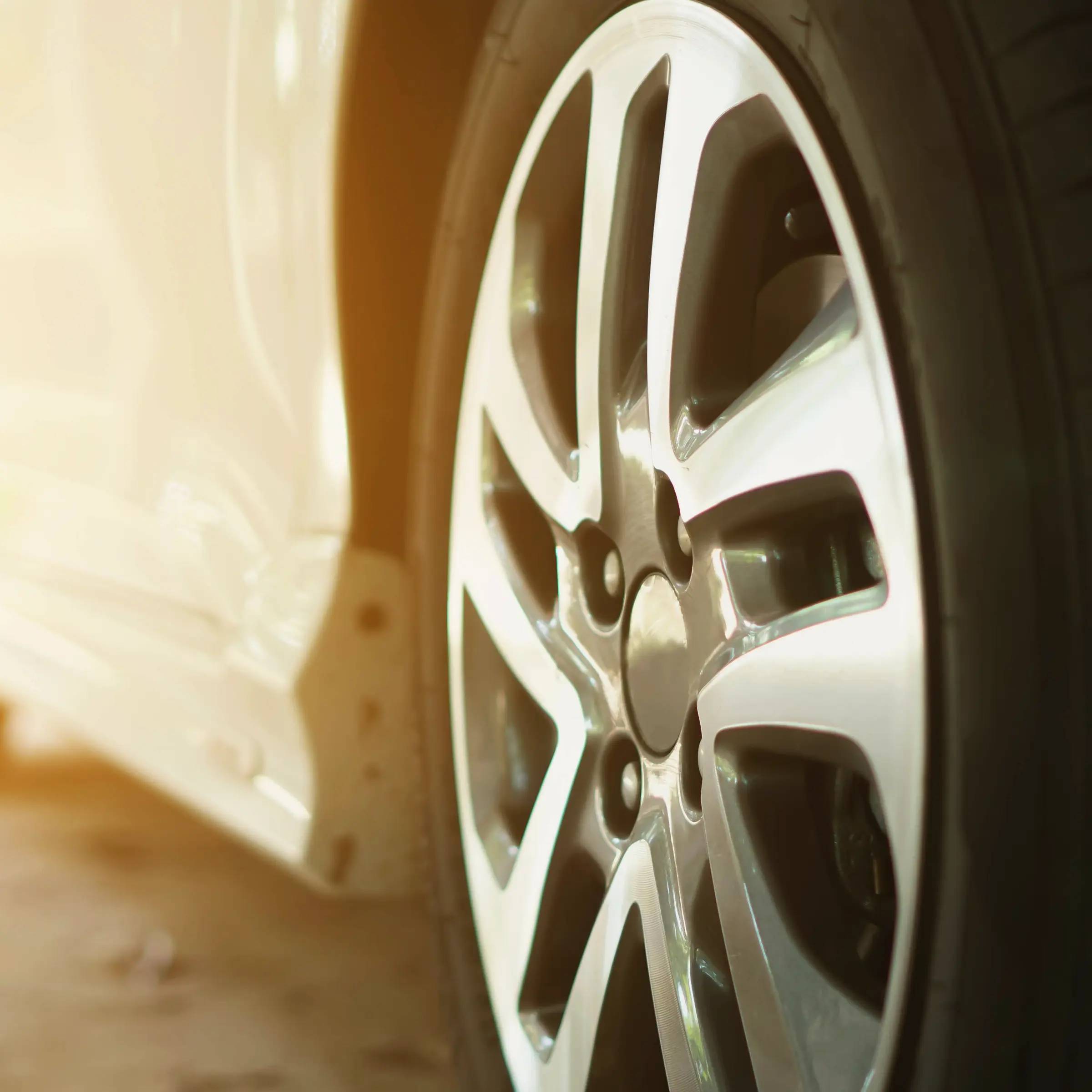 Photo close up of wheel on a silver car with sun shining