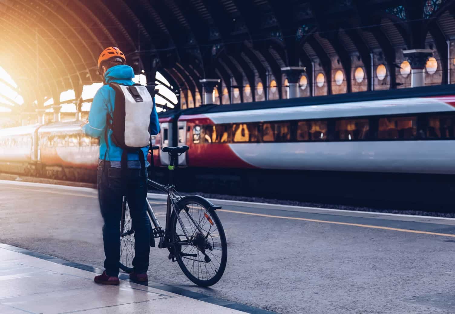 A man standing on a train station platform with his bike 