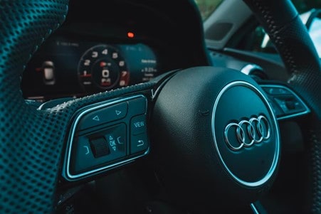 An Audi steering wheel showing buttons, signals and electrics behind it  