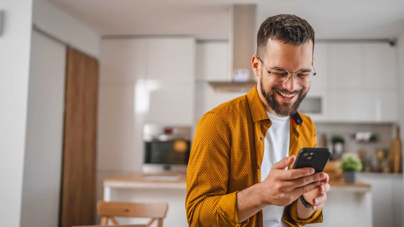 Man with eyeglasses stand at home use mobile phone sms texting