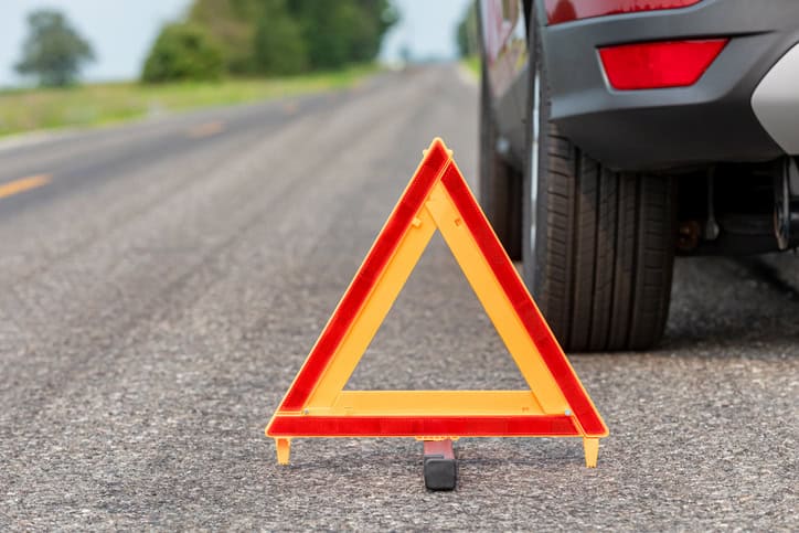 Car breakdown on side of road with warning triangle