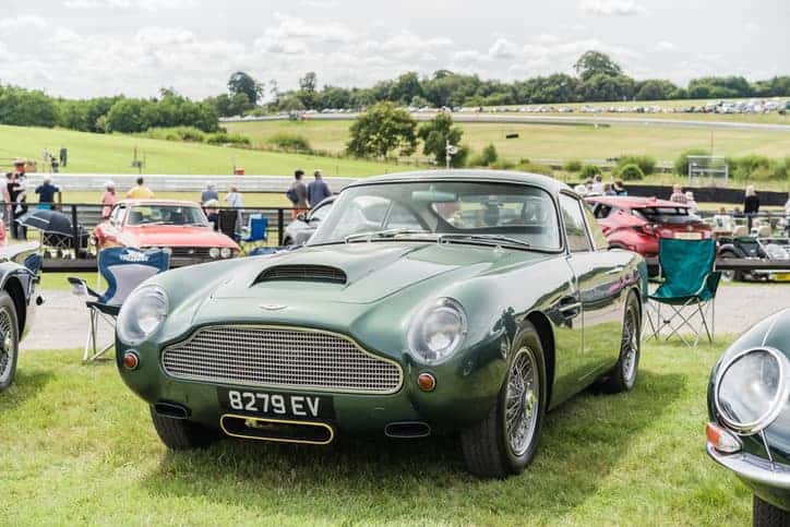 A green Aston Martin DB4 GT is displayed at a classic car meet