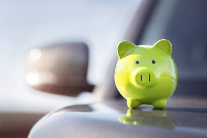 A green piggy bank placed on a car bonnet