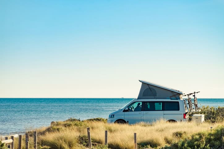 A van with the top open parked overlooking the sea